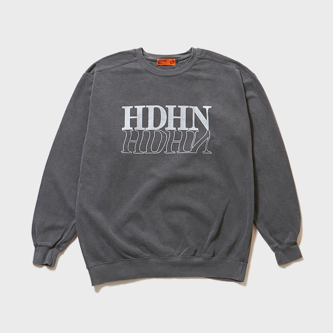 Product Front Photo: A pigment-dyed (coloring technique) cool sweatshirt in black with a dark grey appearance. On the chest, a large HDHN (abbreviation for HOTDOG HUNTER) logo is silk-screen printed, resembling a reflection on water and a mirror. The print is in light grey and is single-colored.